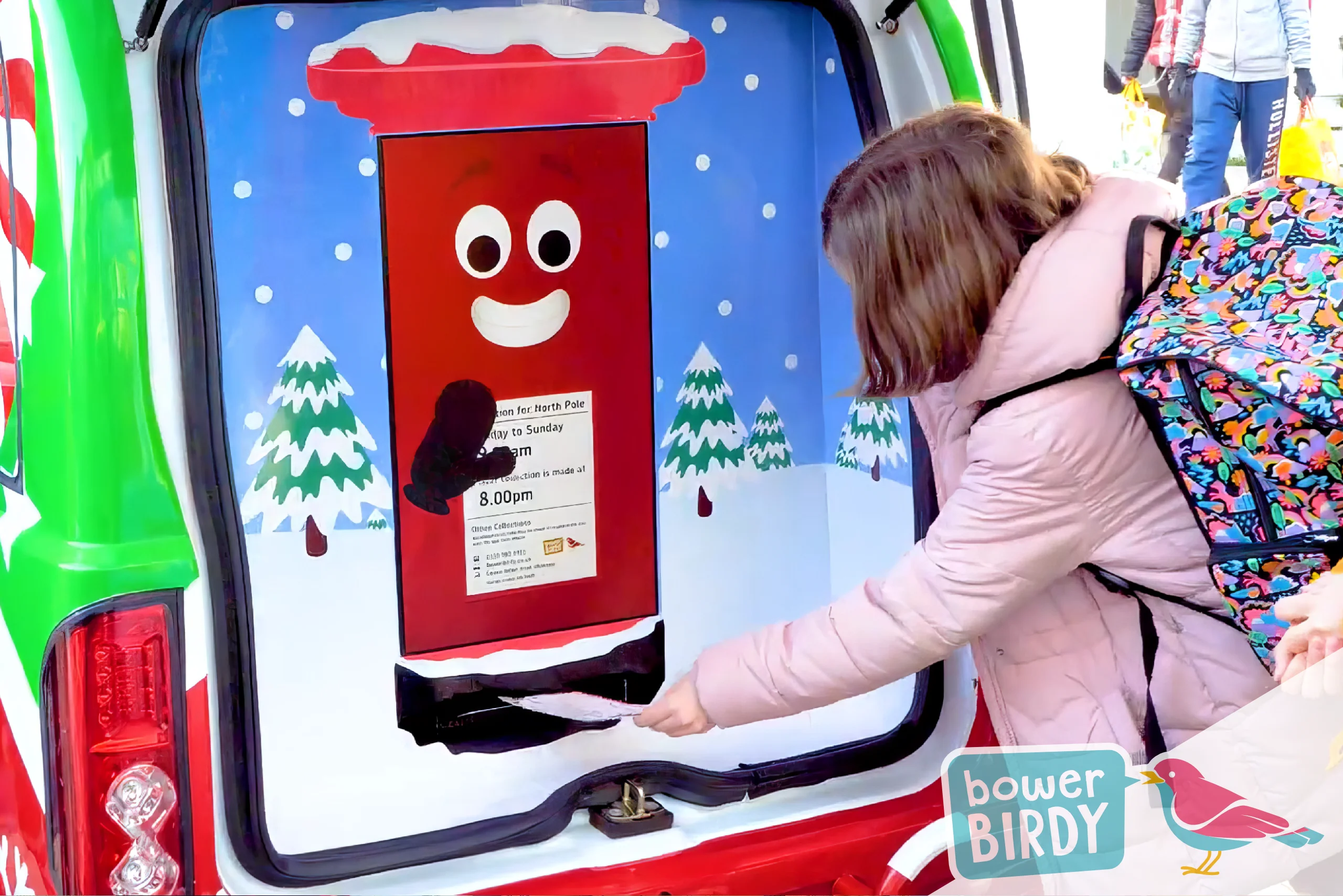 A young girl posts her Christmas list into the Enchanted Postbox in the boot of the Elf Car