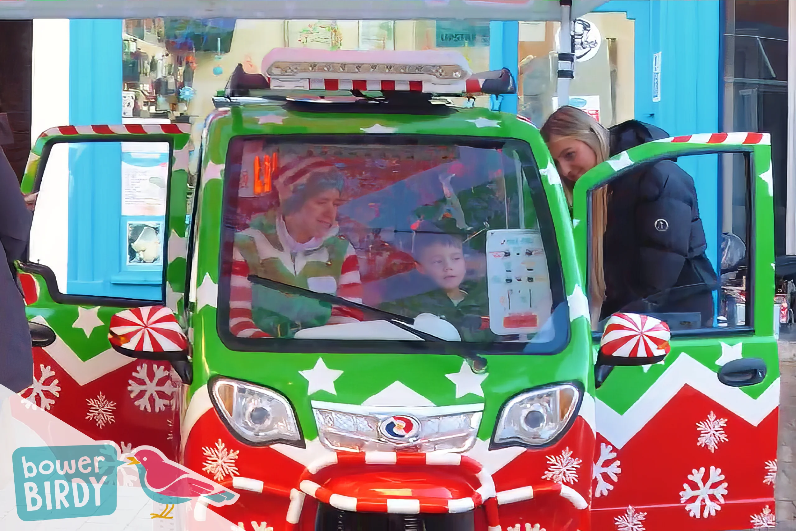A Bowerbirdy elf sits inside the Elf Car with a young guest, who's video calling Santa