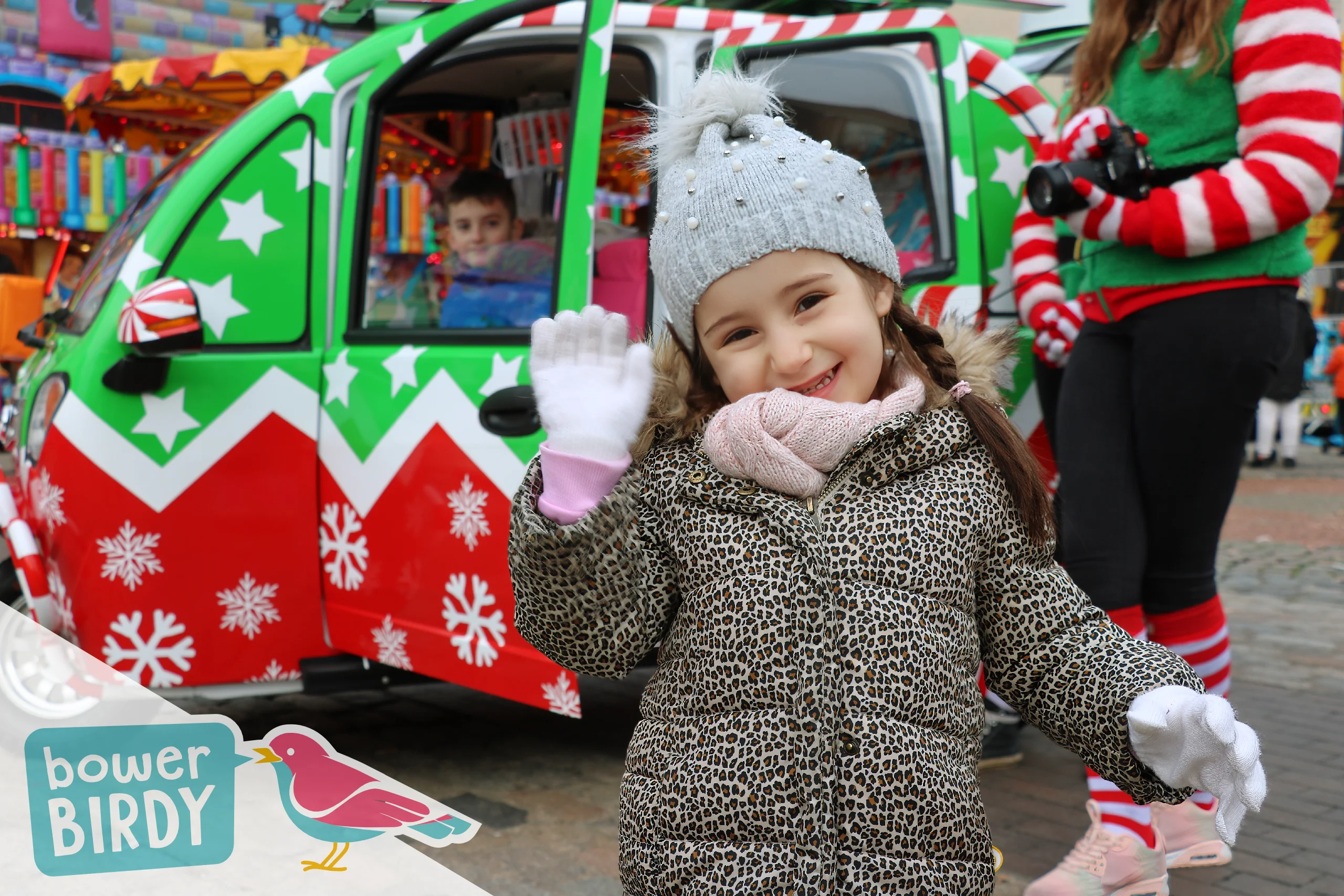 Elf Car Christmas Event: A happy young girl smiles and waves in front of the Elf Car