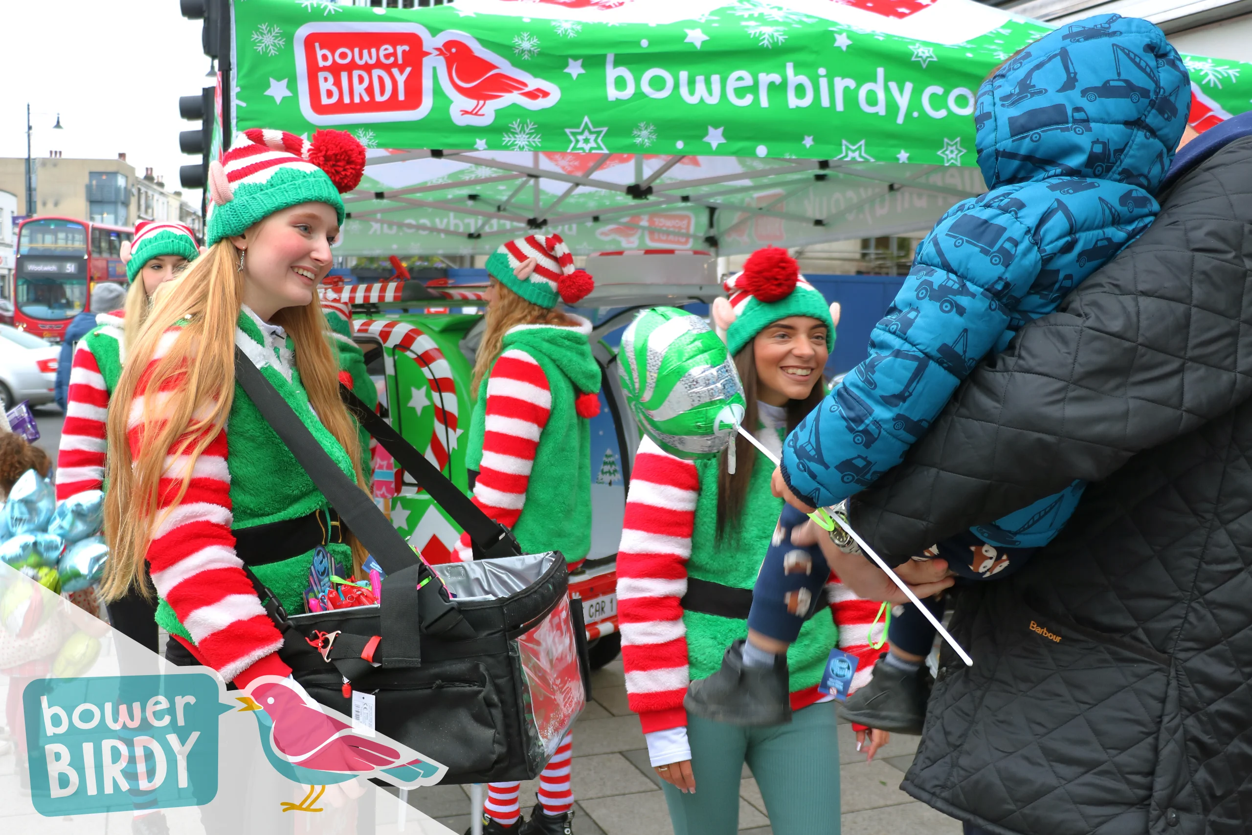 Christmas Fun with the Magical Elf Car: Two Bowerbirdy elves talk to a child being held by their dad.