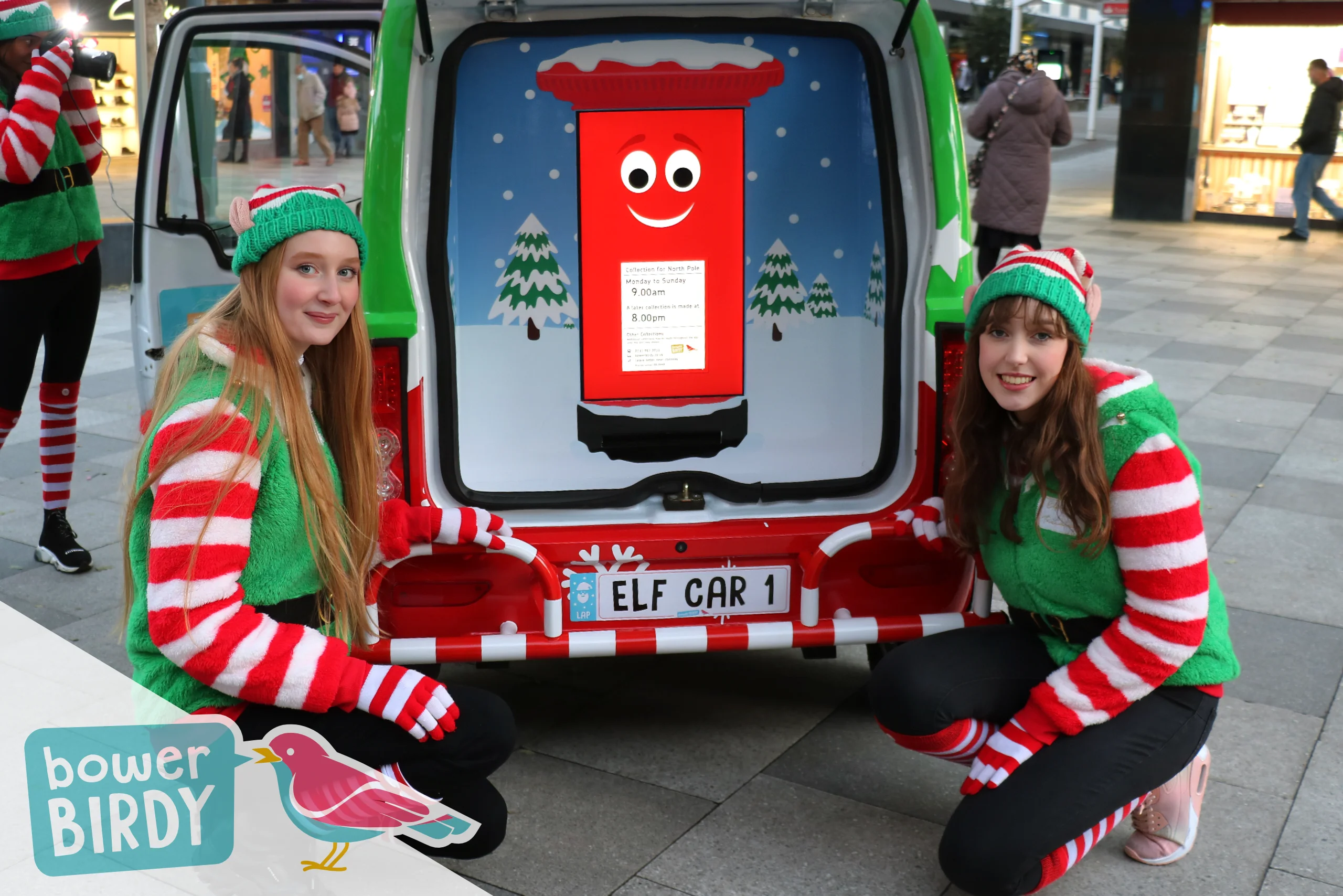 Elf Car Christmas Magic in Stevenage: Two smiling Bowerbirdy elves crouch down eitehr side of Elf Car boot - inside of which is the Enchanted Postbox