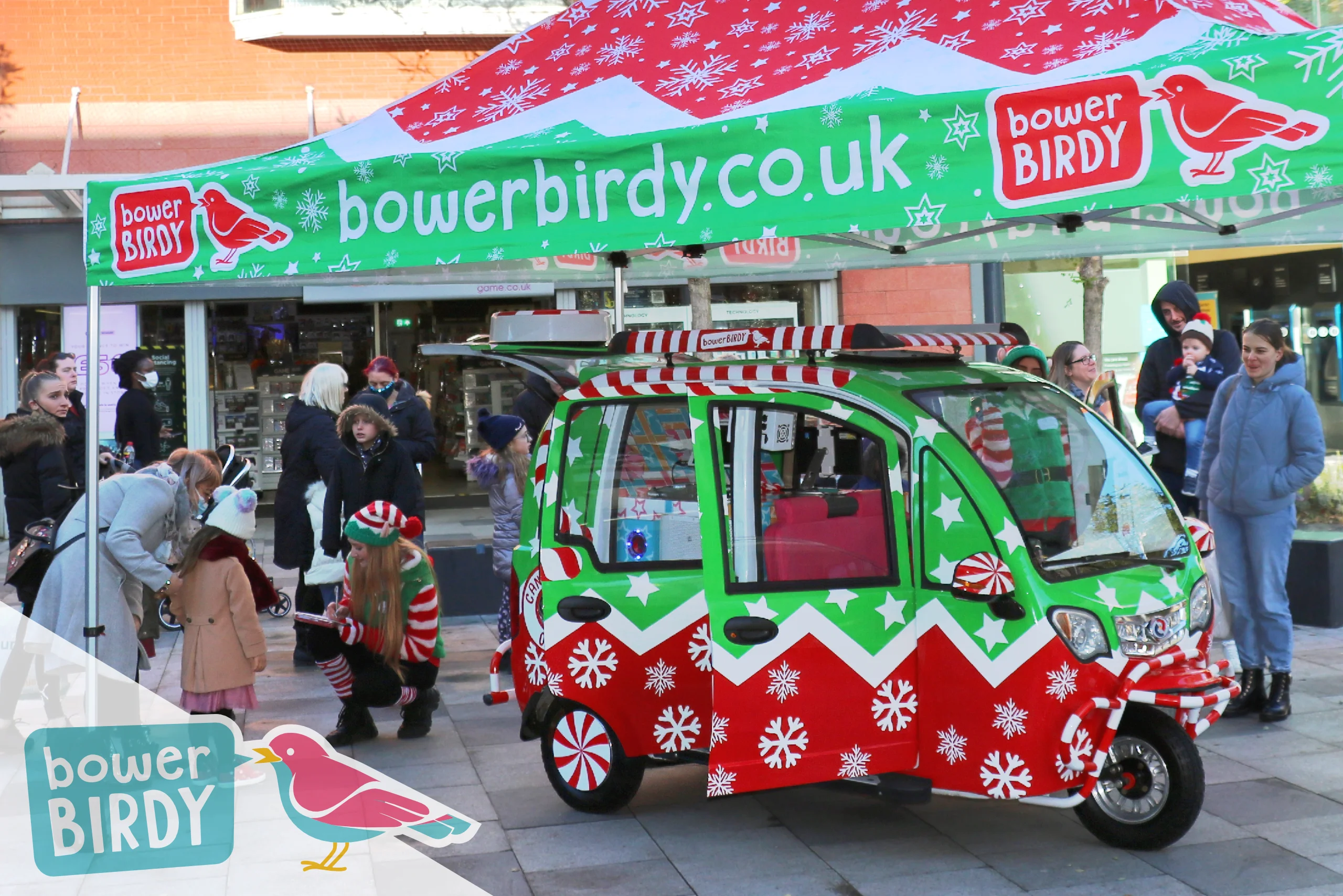 Elf Car Christmas Magic in Stevenage: The Elf Car is parked under a Bowerbirdy Christmas gazebo with a crowd of visitors around it.