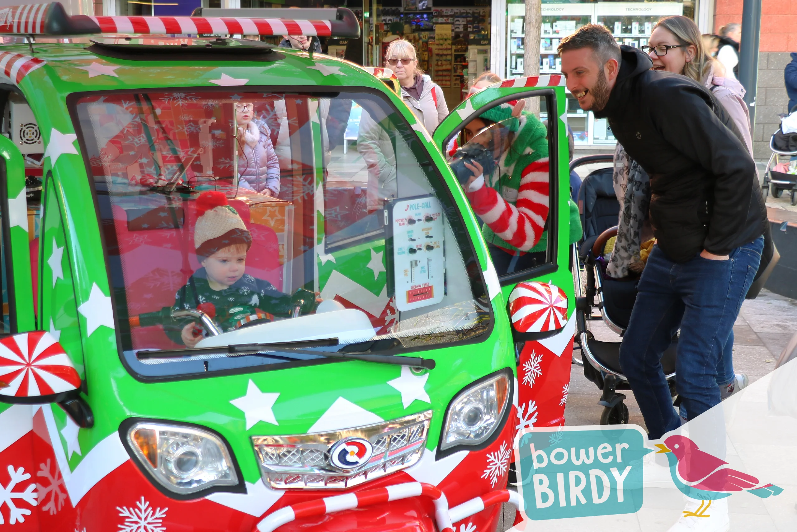 Elf Car Christmas Magic in Stevenage: A dad smiles watching his young son sitting in in the Elf Car playing with the steering wheel.
