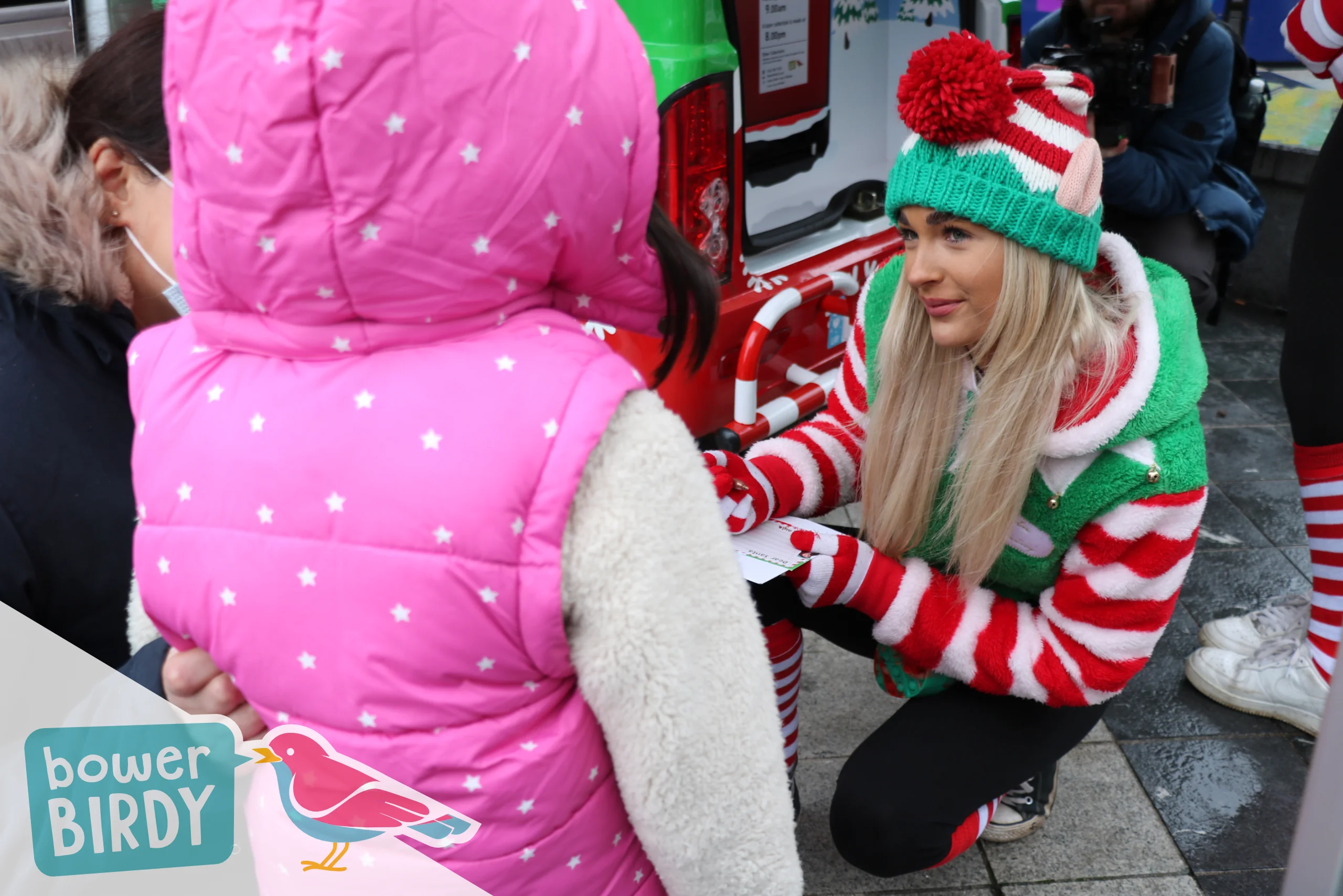 A Bowerbirdy elf helps a young girl to write a Christmas list.