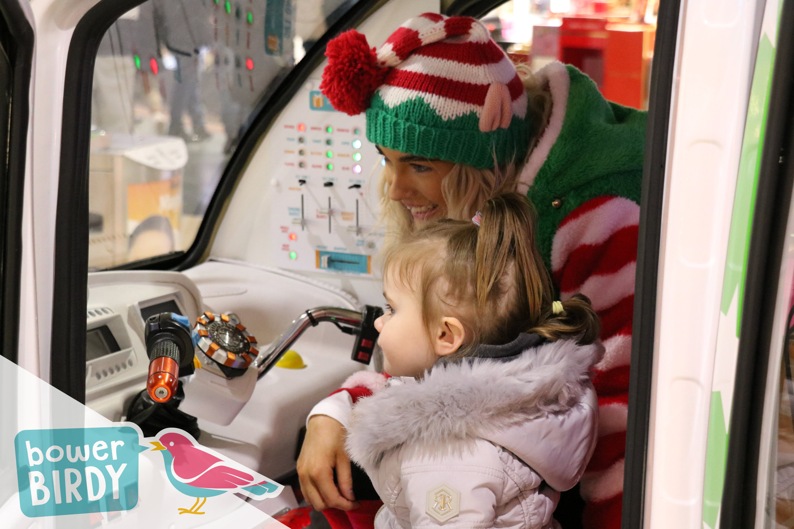 A young girl and a Bowerbirdy elf video call Santa inside the elf car.